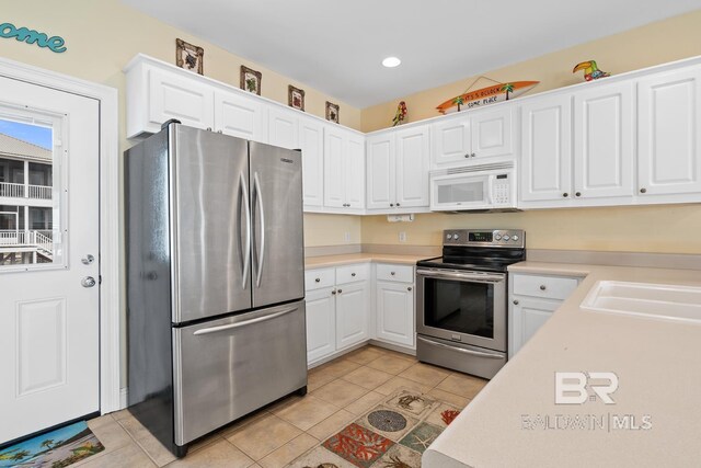 6065 Sawgrass Dr, Gulf Shores, AL 36542 - kitchen with light tile patterned floors, stainless steel appliances, light countertops, and white cabinetry