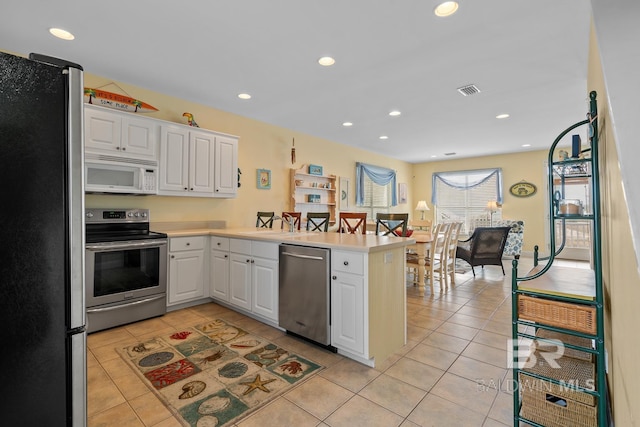 6065 Sawgrass Dr, Gulf Shores, AL 36542 - kitchen featuring a peninsula, white cabinetry, appliances with stainless steel finishes, and light countertops