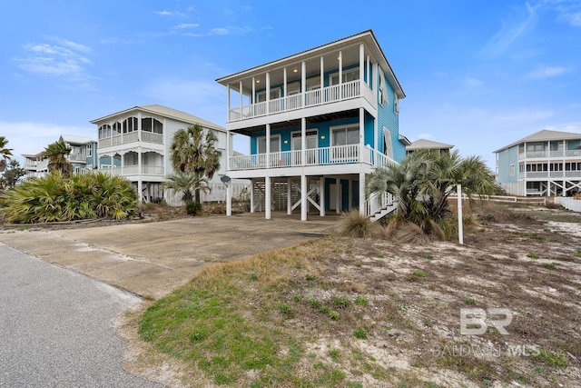 coastal inspired home with driveway, a balcony, and a carport