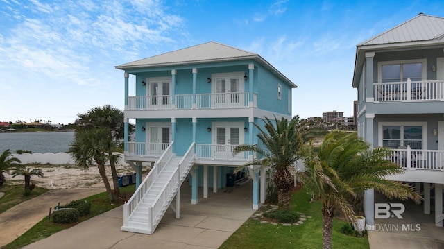 view of front of home with covered porch, a balcony, a carport, and a water view