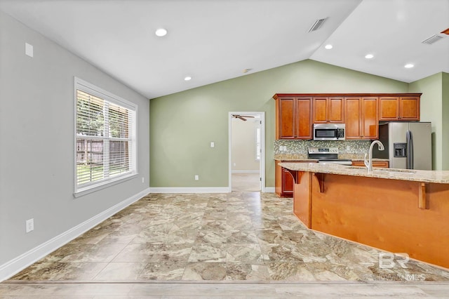 28165 Turkey Branch Dr, Daphne, AL 36526 - kitchen featuring stainless steel appliances, vaulted ceiling, a breakfast bar, decorative backsplash, and light stone countertops