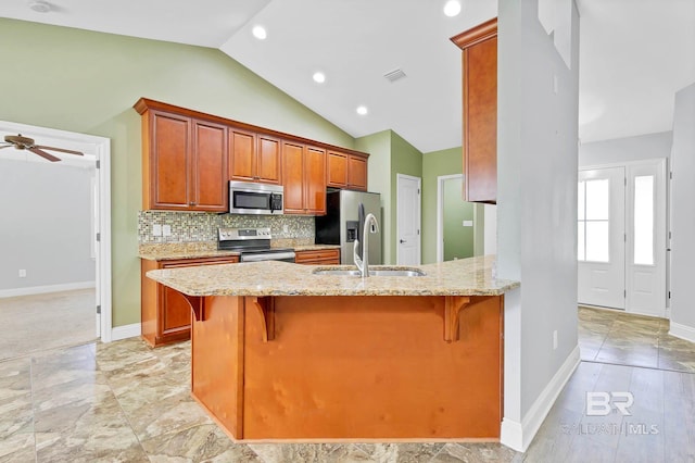 28165 Turkey Branch Dr, Daphne, AL 36526 - kitchen with stainless steel appliances, a sink, light stone counters, lofted ceiling, and baseboards