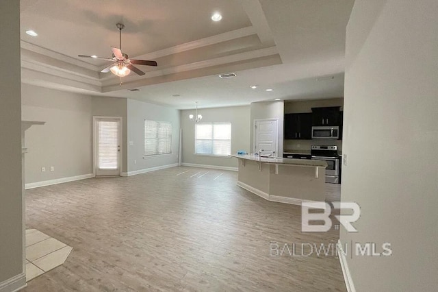 31820 Calder Ct, Spanish Fort, AL 36527 - unfurnished living room with a tray ceiling, light wood-type flooring, ceiling fan, recessed lighting, and a chandelier