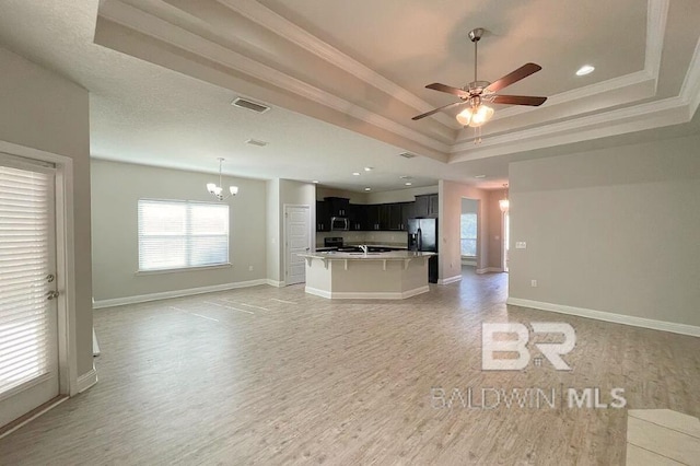 31820 Calder Ct, Spanish Fort, AL 36527 - unfurnished living room with a raised ceiling, a chandelier, light wood-type flooring, healthy amount of natural light, and ornamental molding