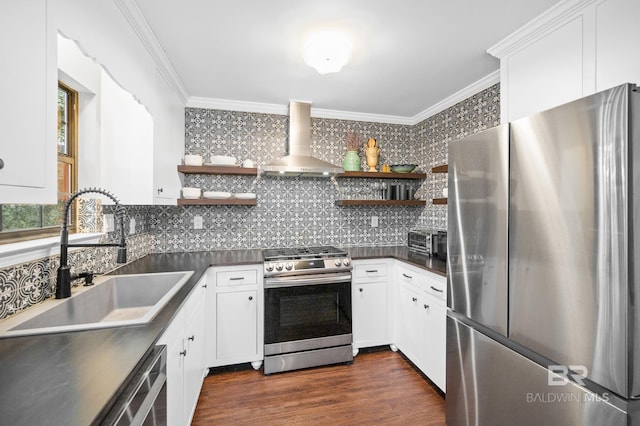 kitchen with appliances with stainless steel finishes, sink, white cabinets, ornamental molding, and wall chimney range hood