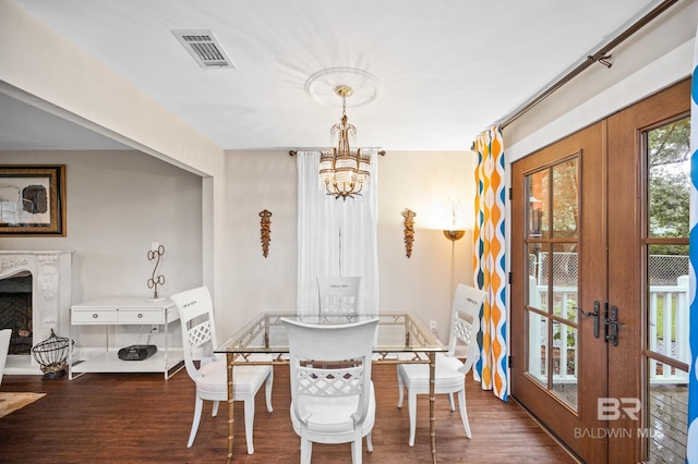 dining area with a fireplace, a notable chandelier, dark wood-type flooring, and french doors