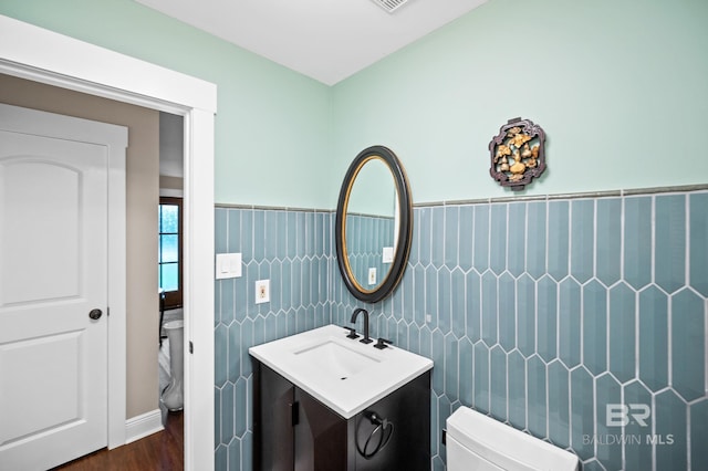bathroom featuring vanity, toilet, wood-type flooring, and tile walls