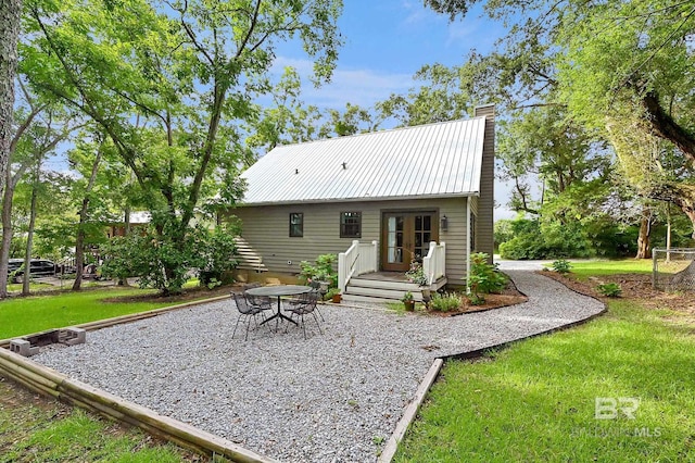 back of house featuring french doors and a lawn