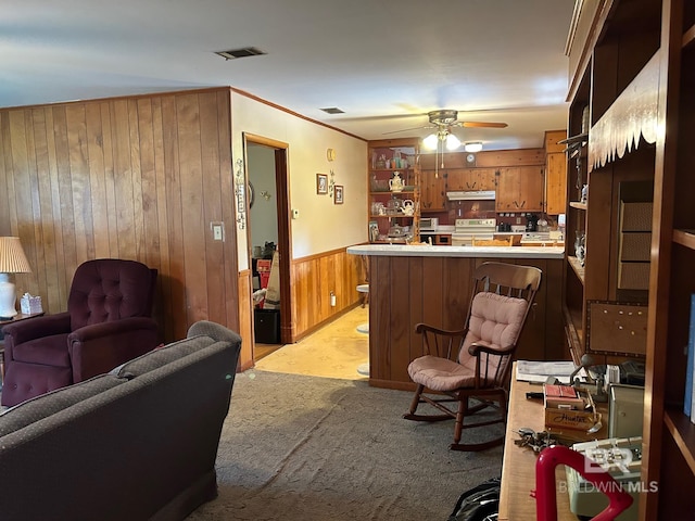 carpeted living room featuring wooden walls and ceiling fan