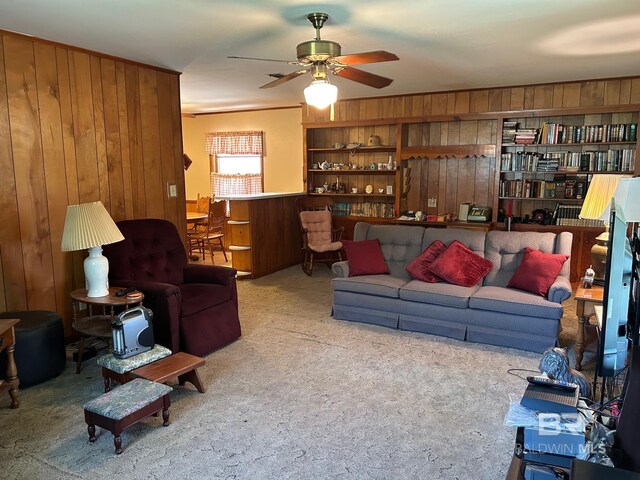 living room featuring ceiling fan, carpet floors, and wooden walls