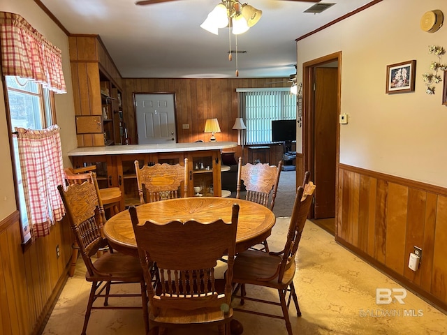 dining room with wood walls, ceiling fan, and a healthy amount of sunlight