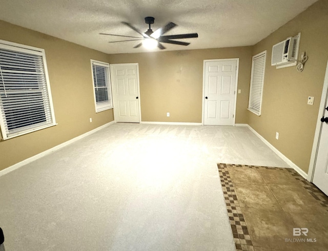 unfurnished room with ceiling fan, light carpet, a wall unit AC, and a textured ceiling