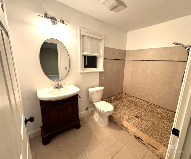 bathroom featuring toilet, tile floors, a tile shower, and vanity