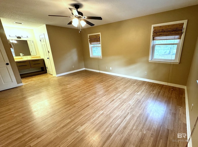 interior space featuring ceiling fan, light hardwood / wood-style floors, and a textured ceiling