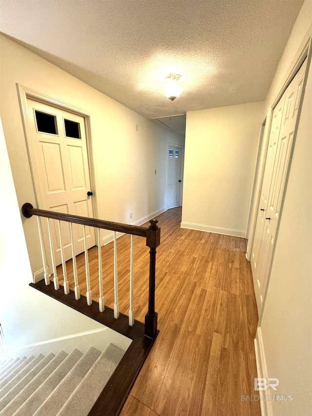 stairway with a textured ceiling and hardwood / wood-style floors