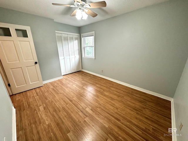 unfurnished bedroom featuring ceiling fan, a closet, light hardwood / wood-style floors, and a textured ceiling