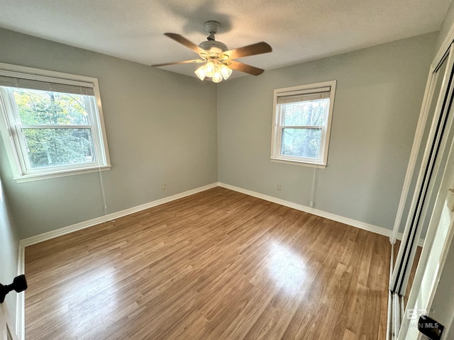 empty room featuring plenty of natural light, ceiling fan, and hardwood / wood-style flooring