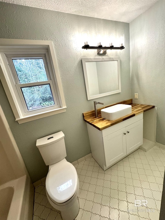 bathroom featuring a textured ceiling, tile floors, vanity with extensive cabinet space, and toilet