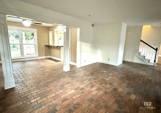 unfurnished living room with ceiling fan and decorative columns