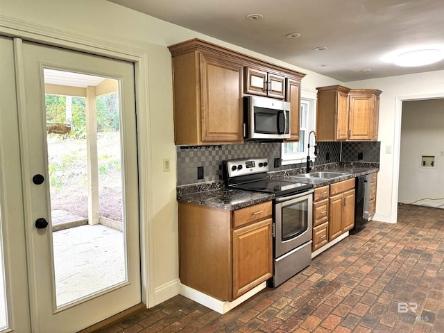 kitchen with dark stone countertops, tasteful backsplash, sink, and stainless steel appliances