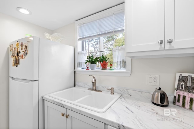 kitchen with white cabinets, white fridge, and sink