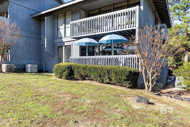 rear view of house with a lawn, a balcony, and central air condition unit