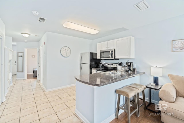 kitchen with visible vents, appliances with stainless steel finishes, a kitchen bar, and a peninsula