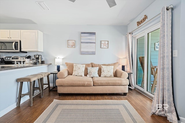 living area with dark wood-style floors, visible vents, and baseboards