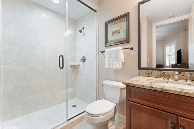 bathroom featuring vanity, tile flooring, toilet, a shower with shower door, and ornamental molding