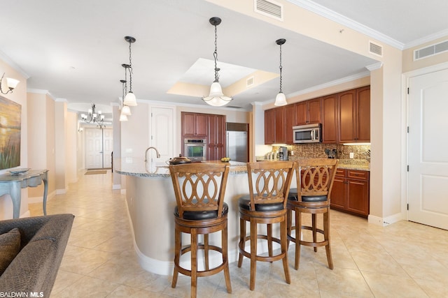 kitchen with an inviting chandelier, a kitchen bar, pendant lighting, and stainless steel appliances