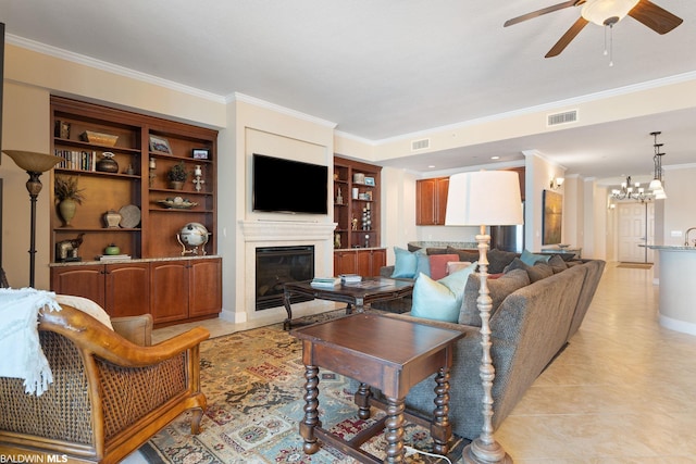 living room featuring light tile flooring, built in shelves, ornamental molding, and ceiling fan with notable chandelier