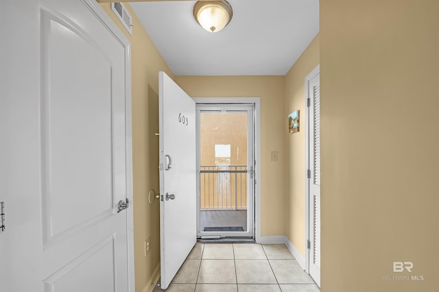 doorway to outside with light tile patterned floors, visible vents, and baseboards