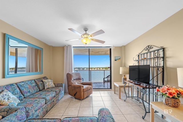 living area featuring a ceiling fan, a wall of windows, and light tile patterned floors