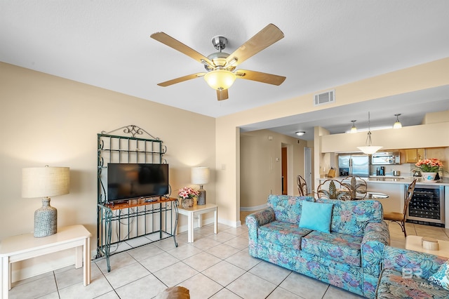 living area featuring light tile patterned floors, beverage cooler, visible vents, and ceiling fan