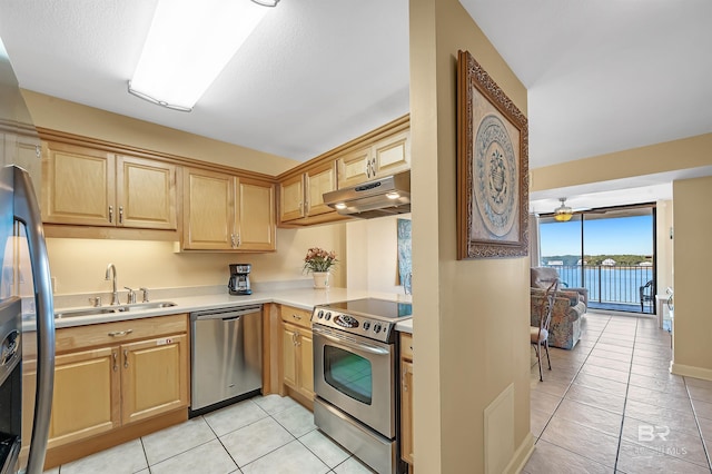 kitchen with stainless steel appliances, light countertops, light tile patterned flooring, a sink, and under cabinet range hood