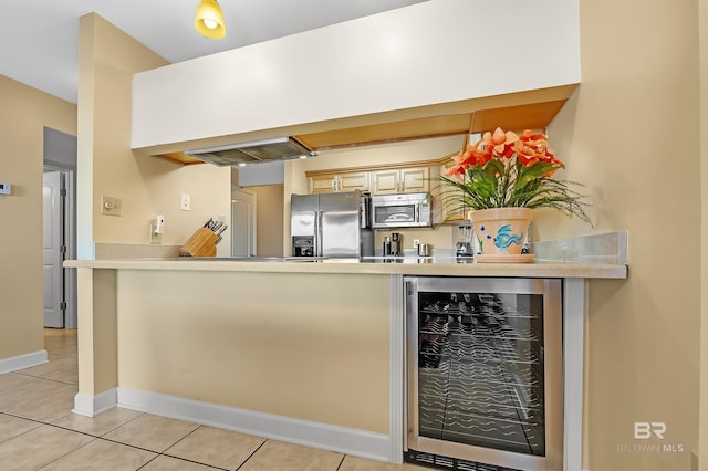 kitchen featuring light tile patterned floors, baseboards, wine cooler, appliances with stainless steel finishes, and a peninsula