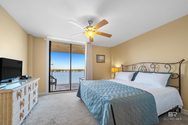 carpeted bedroom with baseboards, ceiling fan, a water view, access to exterior, and expansive windows