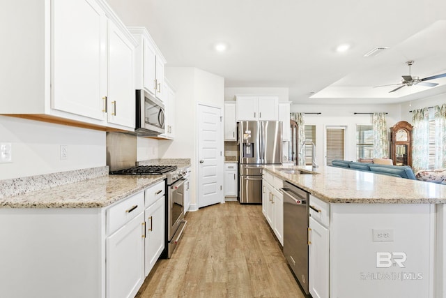 kitchen with white cabinets, sink, stainless steel appliances, and light hardwood / wood-style floors