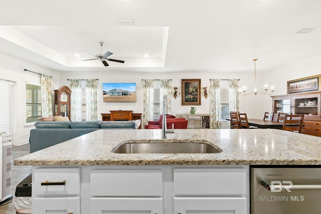 kitchen featuring white cabinets, sink, hanging light fixtures, a raised ceiling, and light stone counters