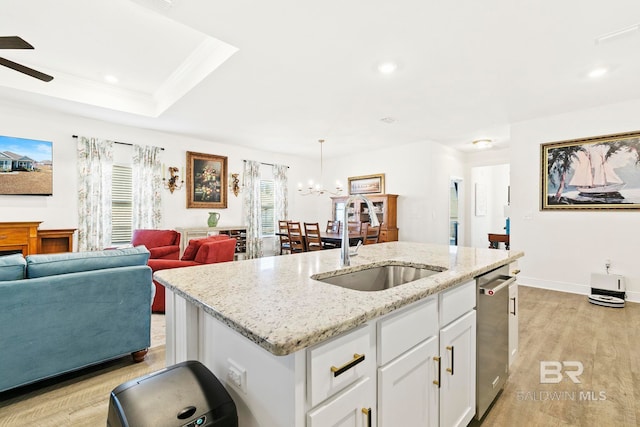 kitchen featuring light hardwood / wood-style flooring, white cabinetry, sink, stainless steel dishwasher, and a center island with sink