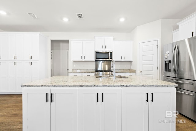 kitchen with white cabinets, stainless steel appliances, and a kitchen island with sink