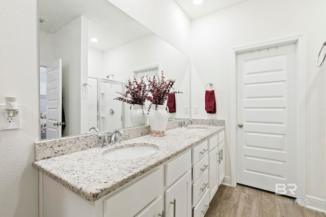 bathroom with an enclosed shower, vanity, and wood-type flooring