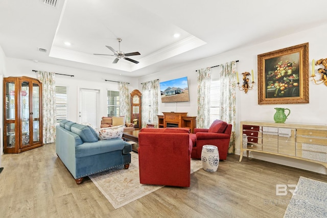 living room featuring ceiling fan, a healthy amount of sunlight, light hardwood / wood-style flooring, and a tray ceiling