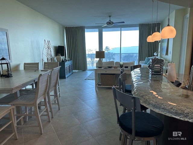 tiled dining room featuring expansive windows and ceiling fan