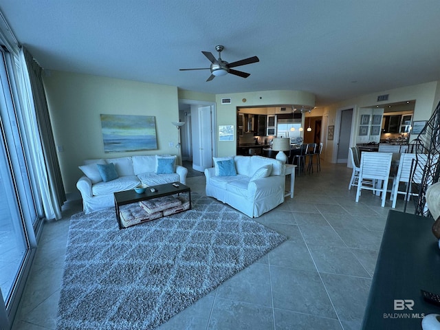 tiled living room featuring ceiling fan, a healthy amount of sunlight, and a textured ceiling