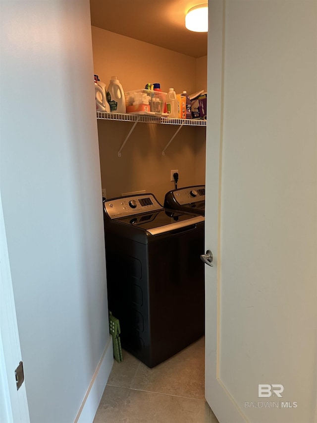 clothes washing area with washing machine and dryer and light tile patterned floors