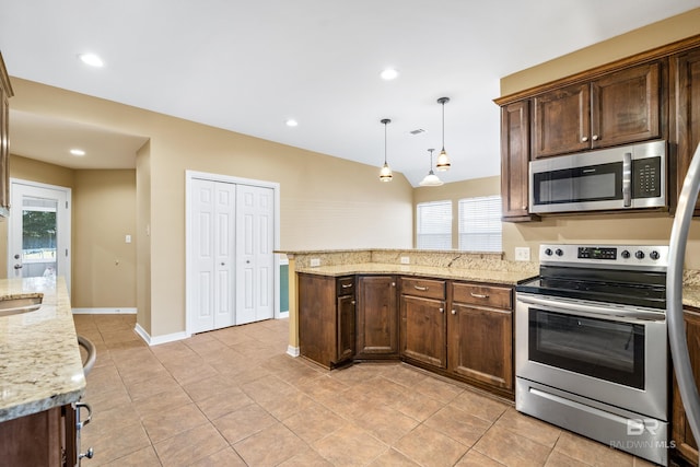 kitchen featuring hanging light fixtures, light stone counters, vaulted ceiling, light tile patterned floors, and appliances with stainless steel finishes