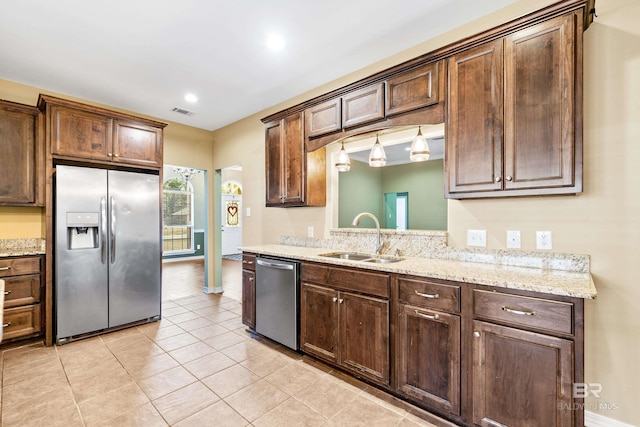 kitchen featuring dark brown cabinetry, light stone counters, sink, and stainless steel appliances