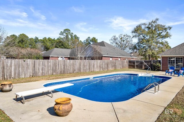 view of pool with a patio and a diving board