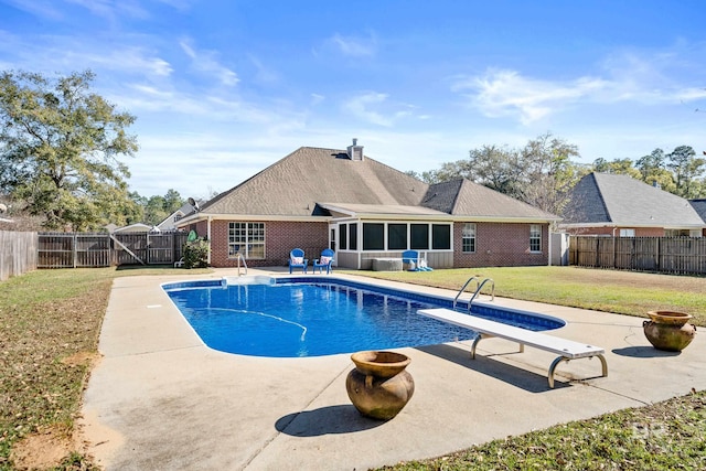 view of swimming pool with a sunroom, a diving board, a yard, and a patio